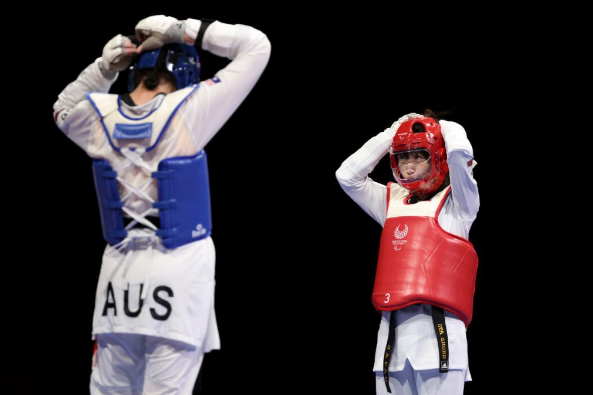 Australia's Janine Watson and Japan's Shoko Ota face each other as they adjust their helmets, preparing for their repechage match.