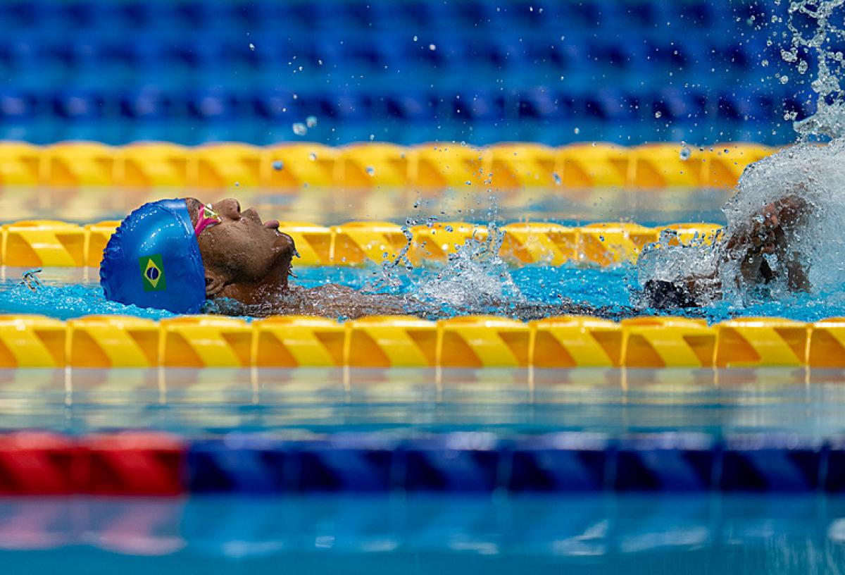 A male Para swimmer swimming backstroke in a pool