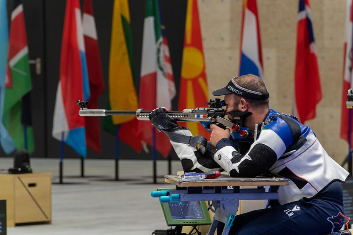 A male athlete shooting with a rifle in a shooting Para sport competition