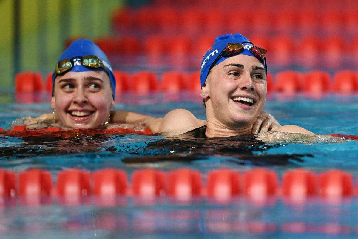 Two female swimmers with Italian caps smiling in a pool