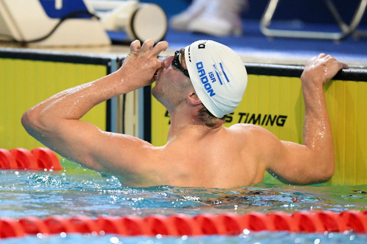 A male swimmer kissing his hand in a pool