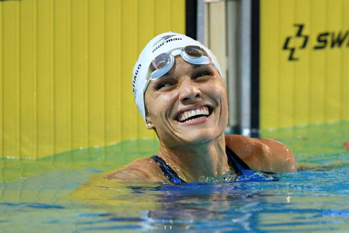A female swimmer smiling from inside a competition pool