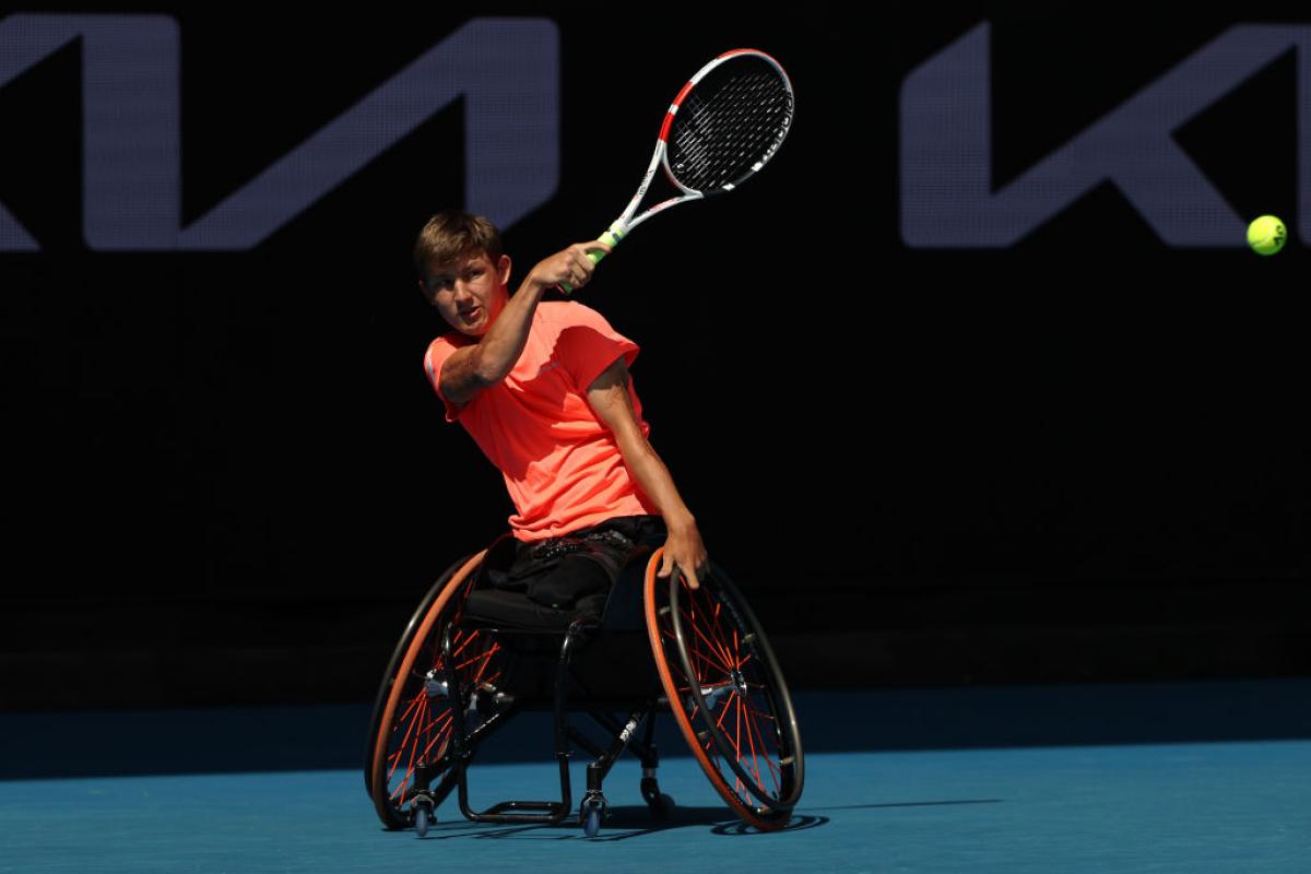 Niels Vink plays in an Australian Open match, his right hand holding his racquet and the other directing his wheelchair.