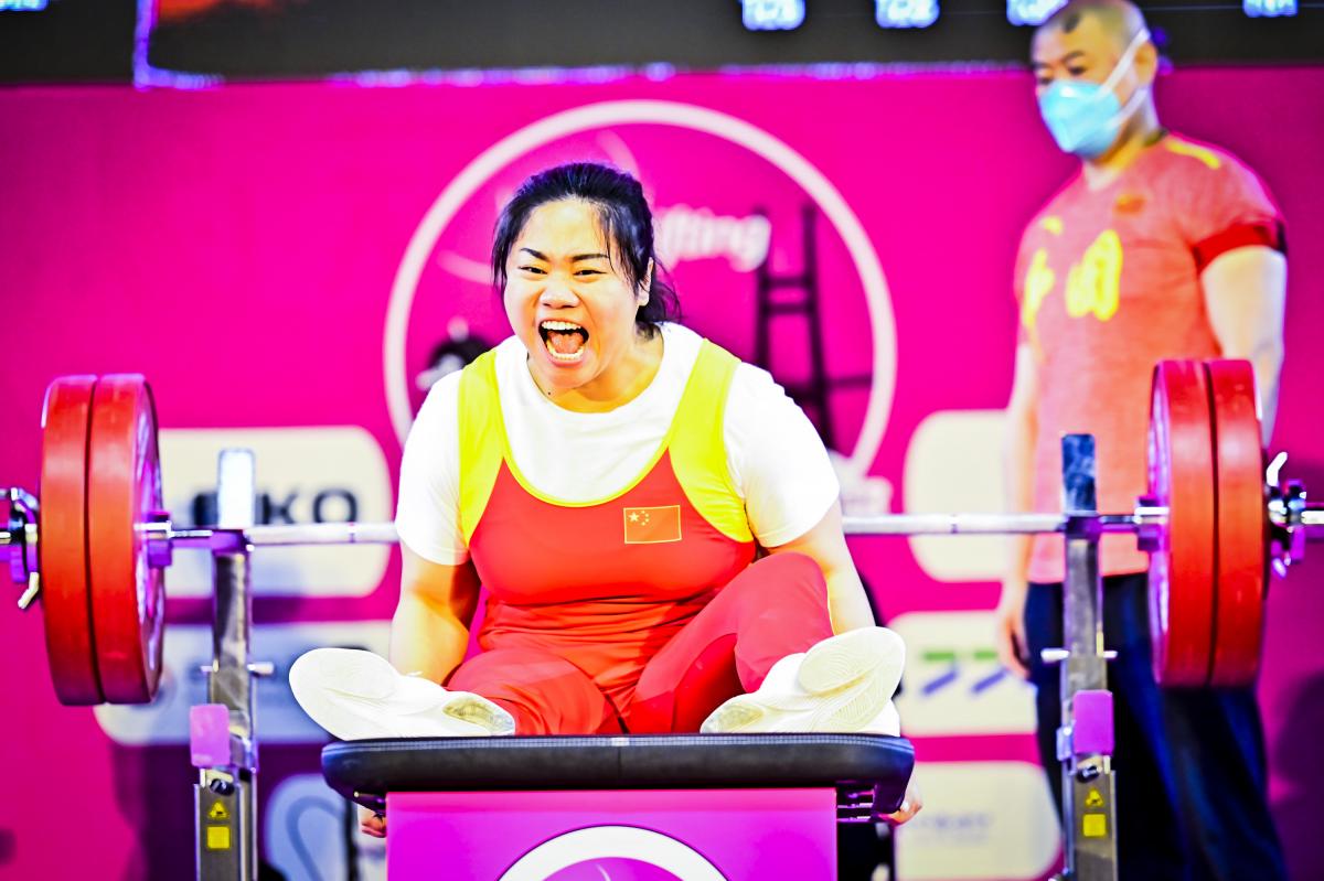 Chinese female Para powerlifter screams in celebration after a successful lift.