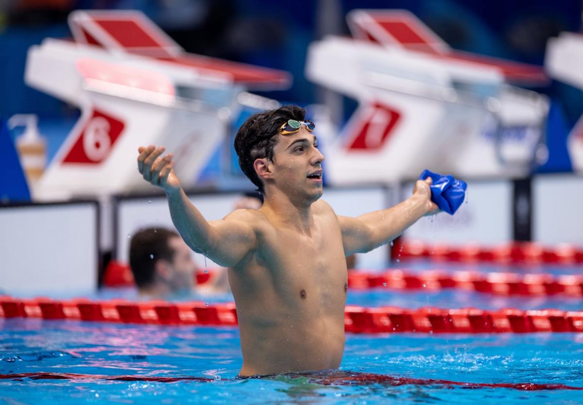 A male celebrates by stretching his hands out after a race.