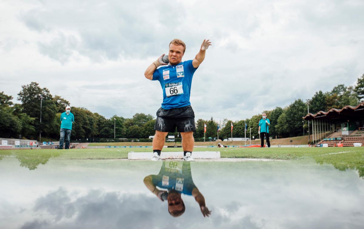 A short stature man competing in shot put