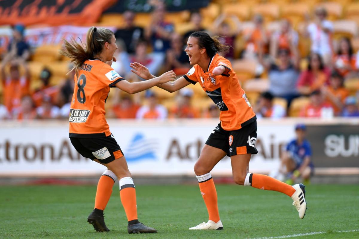 A woman who is missing her left forearm runs towards a teammate in celebration.