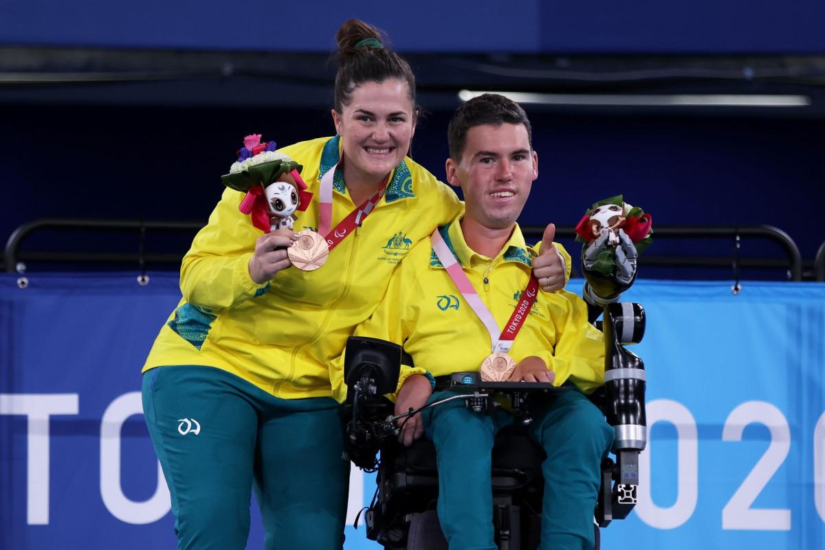 Australian boccia player Daniel Michel and ramp assistant Ashlee McClure smile on the podium after winning bronze at the Tokyo 2020 Paralympic Games.