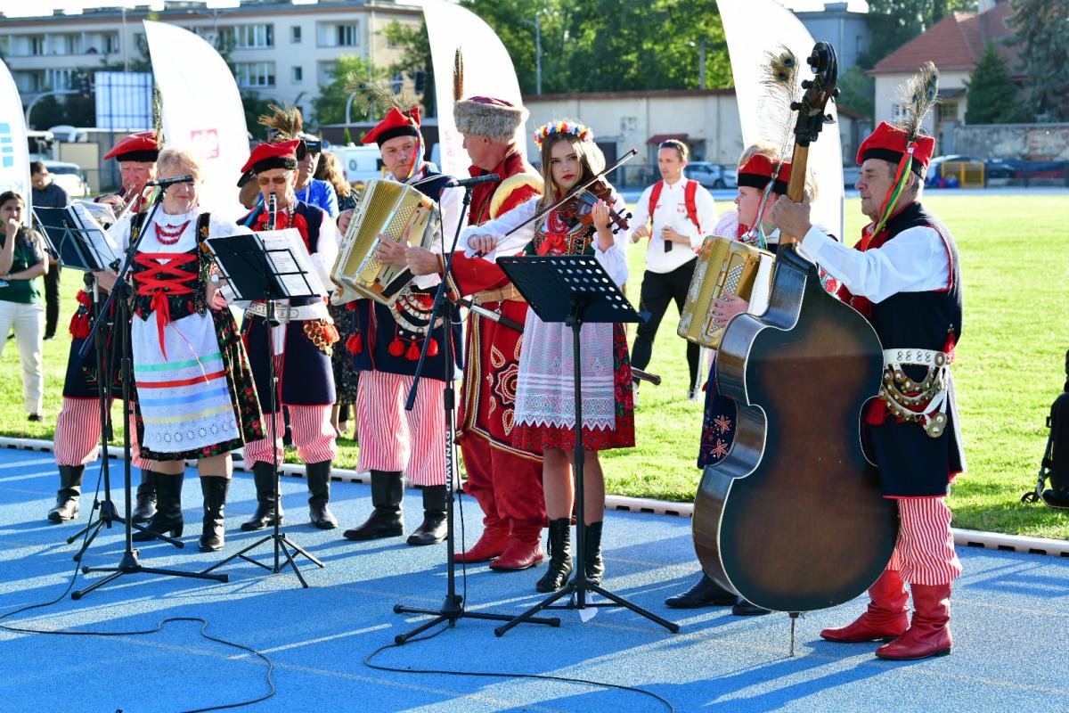 A group of musicians in traditional Polish clothing play on the athletics track in Cracow.