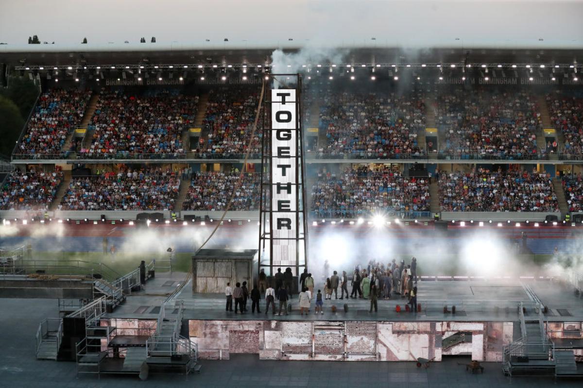 A banner reads 'Together' as post-war Birmingham is recreated onstage during the 2022 Commonwealth Games Closing Ceremony.