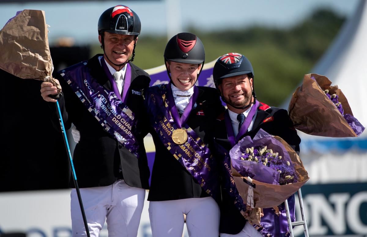 Three athletes smile after receiving their medals at the Para Dressage World Championships.