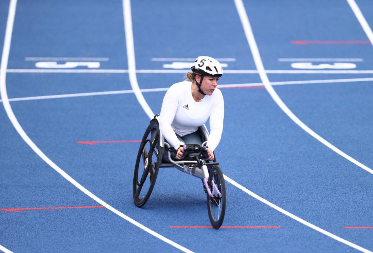 A female wheelchair racer after crossing the line in a blue track