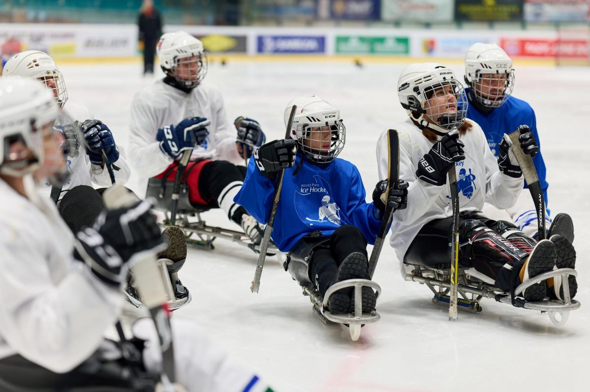 Para ice hockey players hold sticks on the ice.