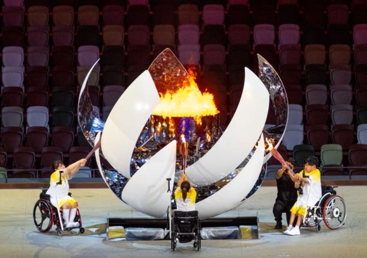 Three athletes on wheelchairs light a sphere-shaped cauldron during the Opening Ceremony of the Tokyo 2020 Paralympic Games.