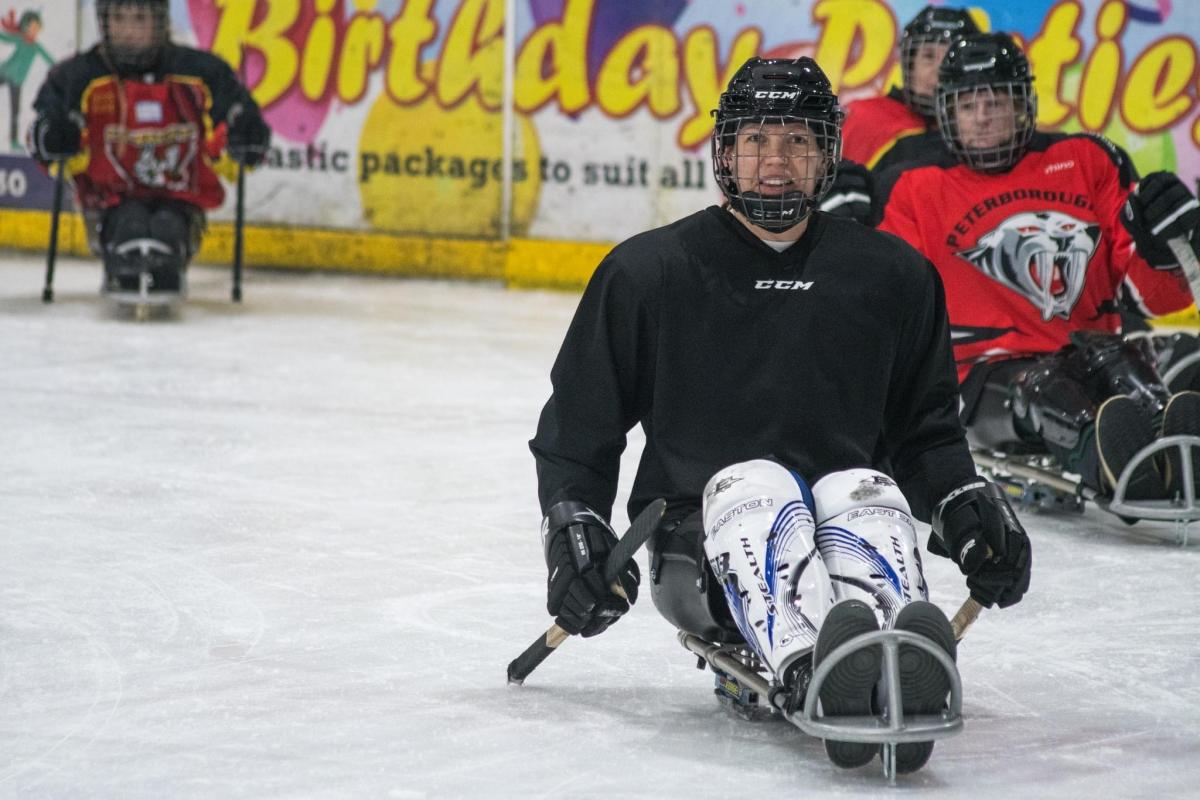 A group of four female Para ice hockey players on an ice rink