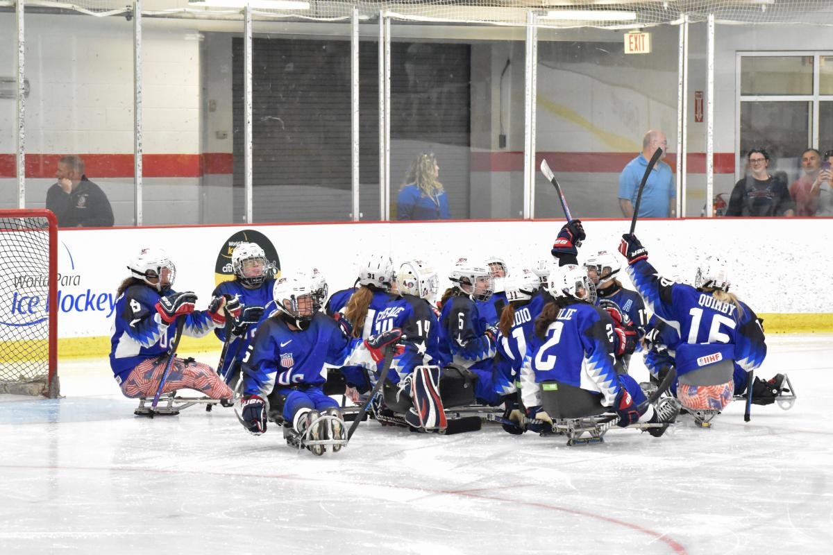 Female Para ice hockey players in blue jerseys celebrate on ice