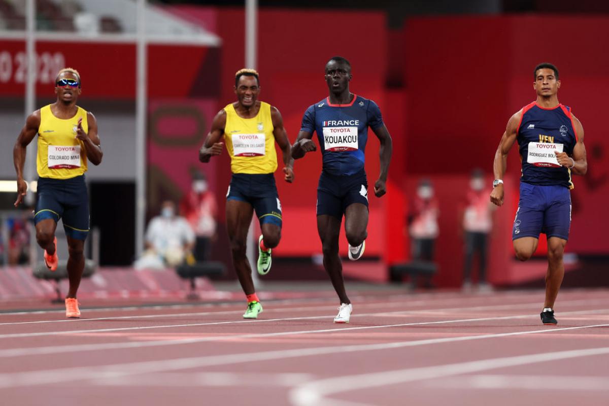 Four men running on an athletics track