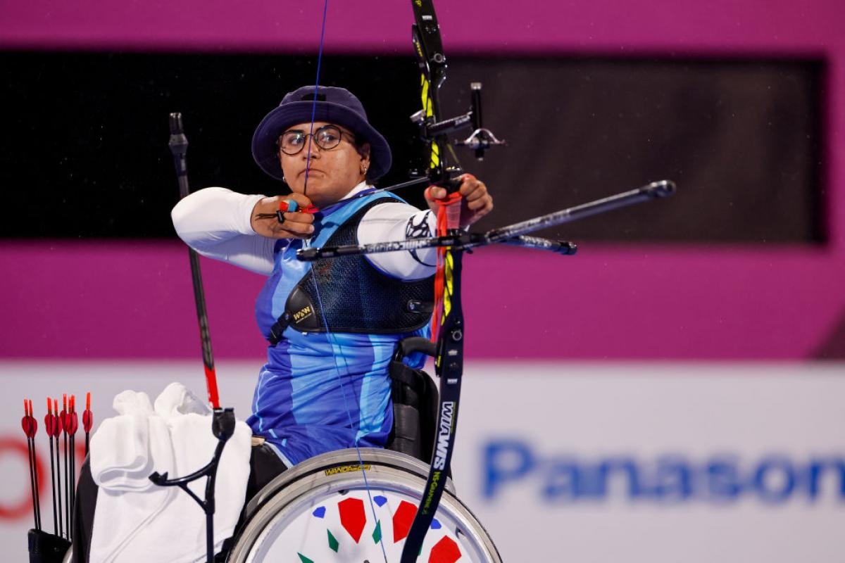 A female athlete on a wheelchair is pulling a bow at the Tokyo 2020 Paralympic Games.
