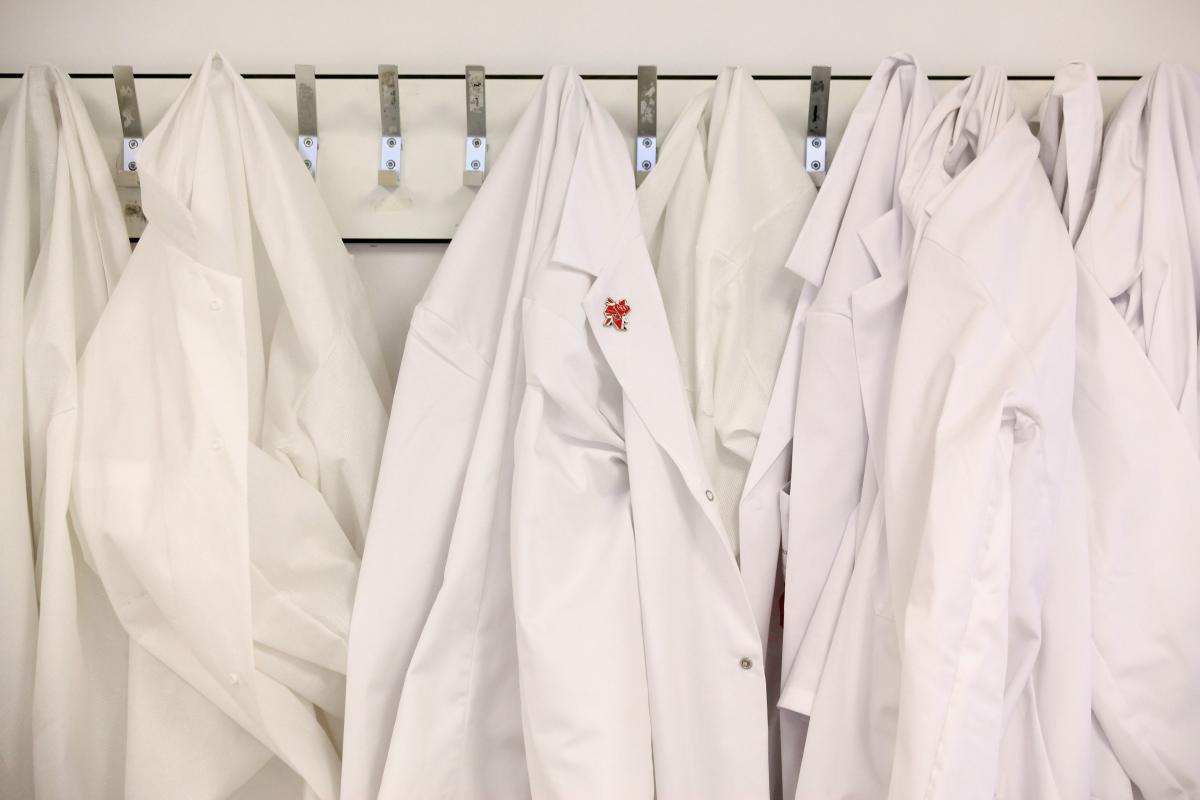 White lab coats hang on the wall in an anti-doping laboratory.