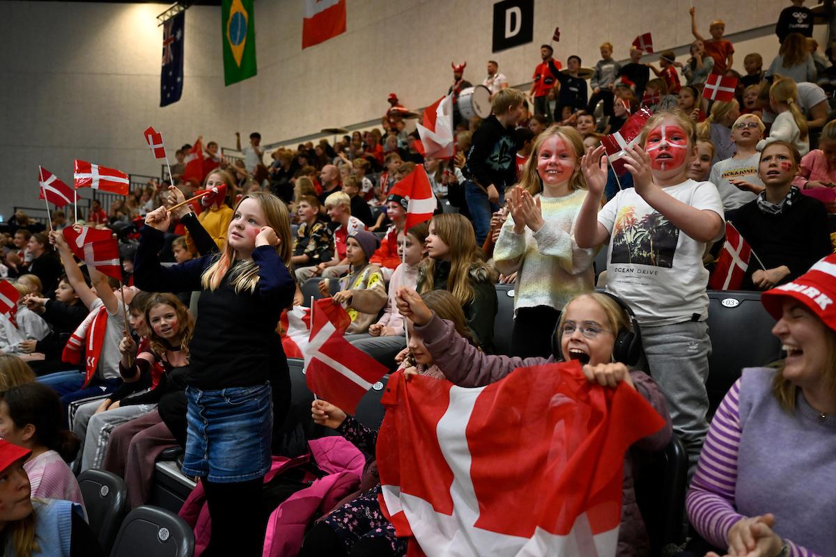 Children holding Denmark's flags fill the stands at a venue