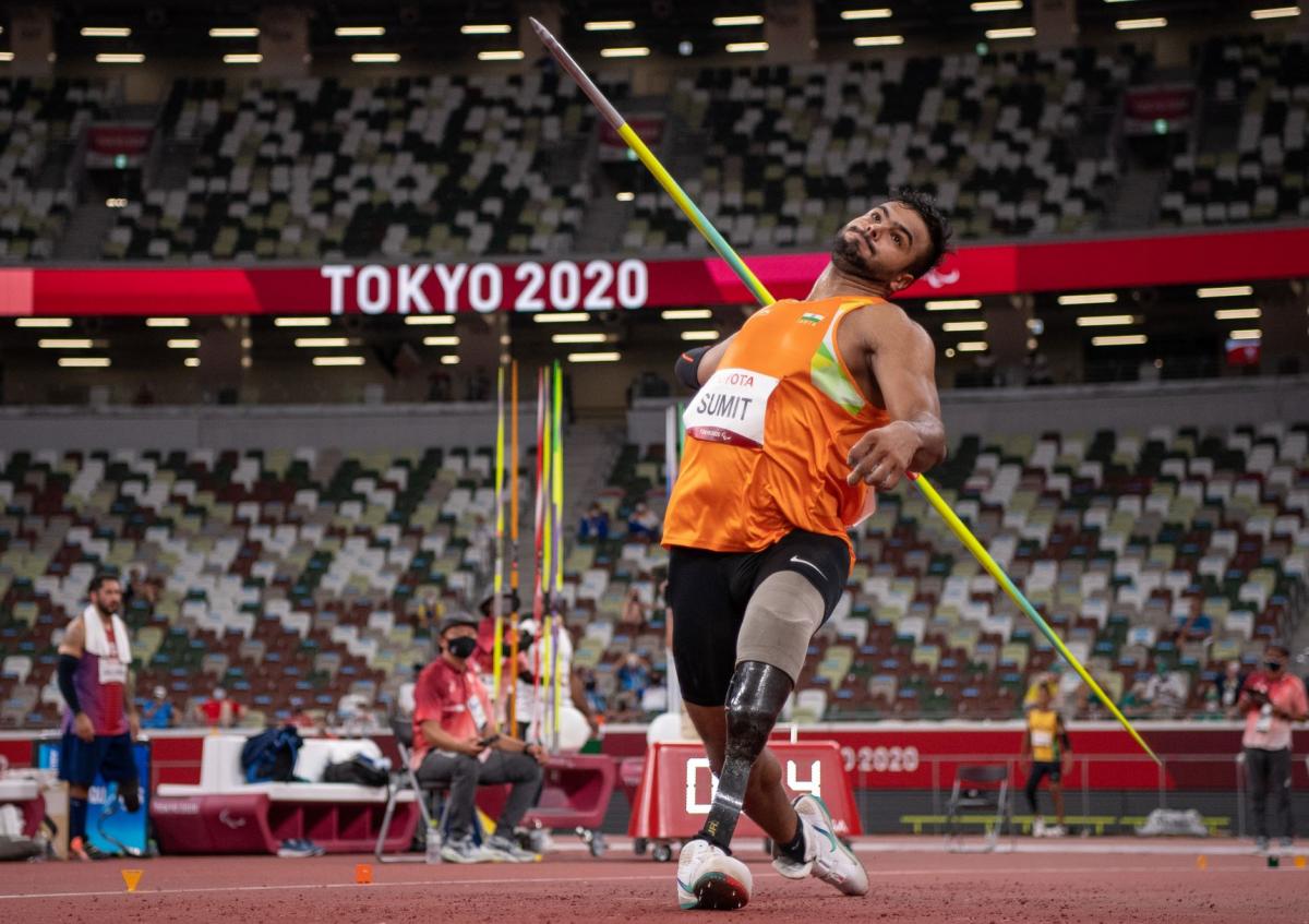 A male athlete with a prosthetic leg steps forward to throw a javelin