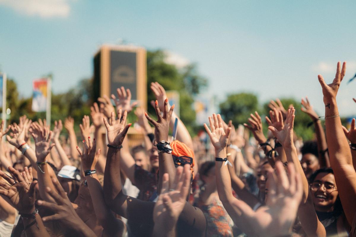 People in a large crowd raise their hands during the Paris 2024 handover celebration.