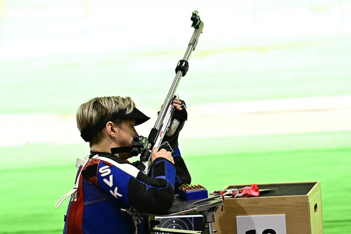 A woman with a rifle in a shooting range during a shooting Para sport competition