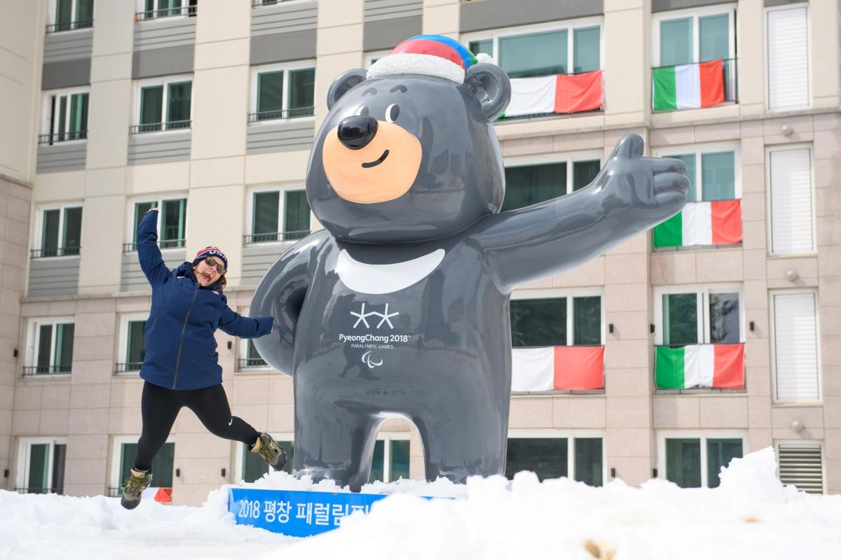 A woman jumps next to a mascot of the Pyeongchang 2018 Paralympic Games