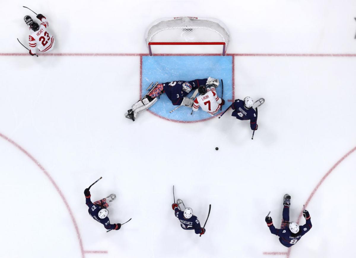 An aerial view of a Para ice hockey game with five players on ice