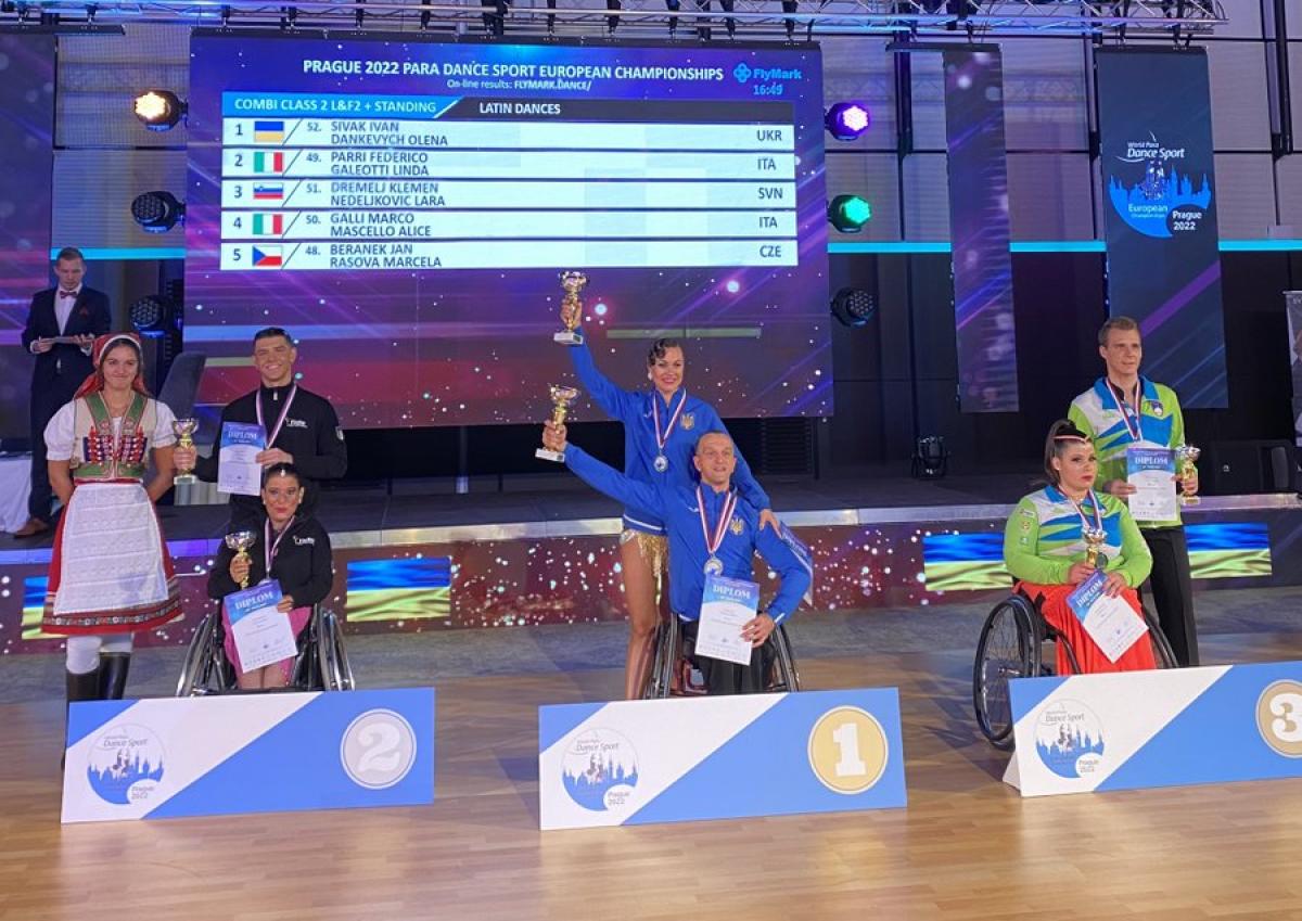 Ukraine's Ivan Sivak (centre) poses on the podium with his dance partner Olena Dankevych after taking the combi class 2 gold medal.