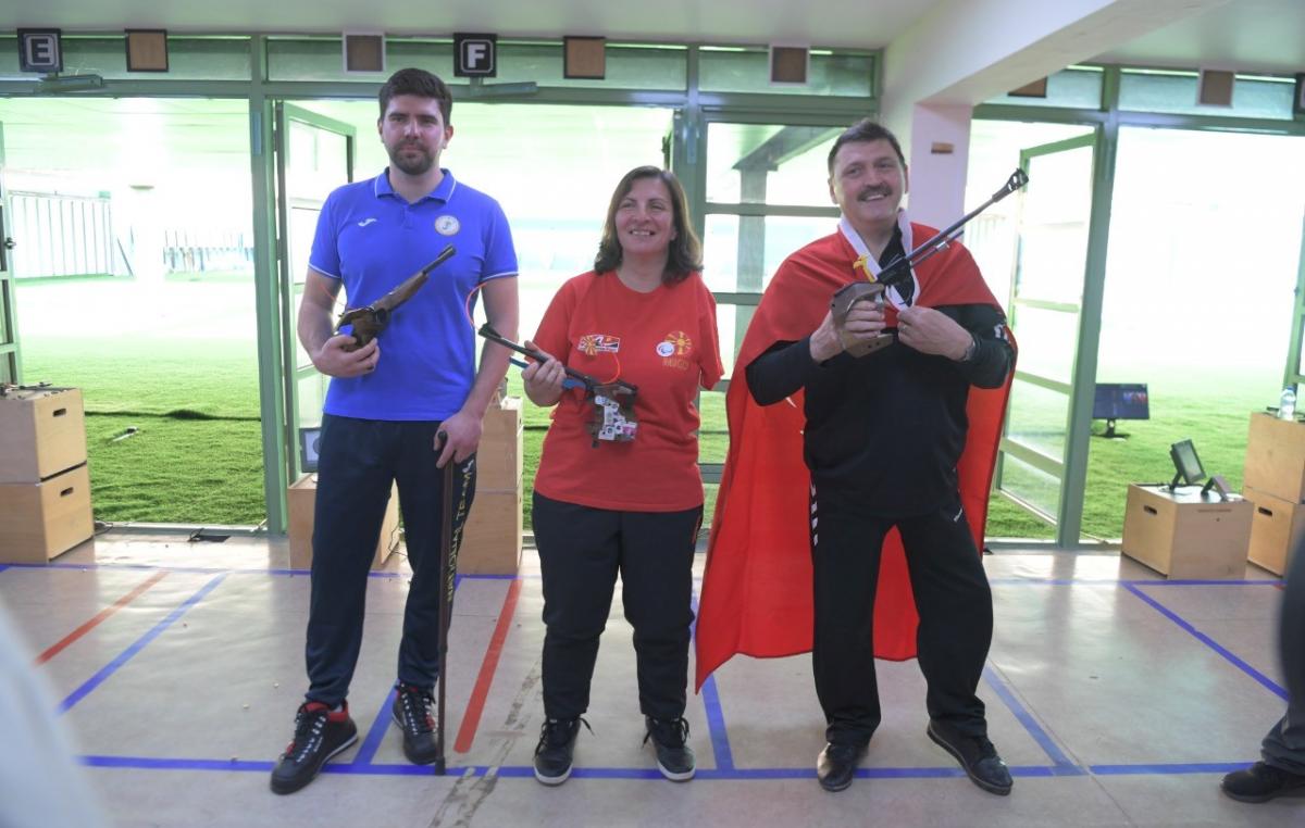 A woman standing between two men in a shooting range