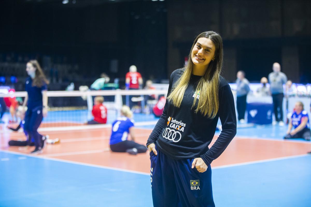 A female athlete smiling in front of a sitting volleyball court