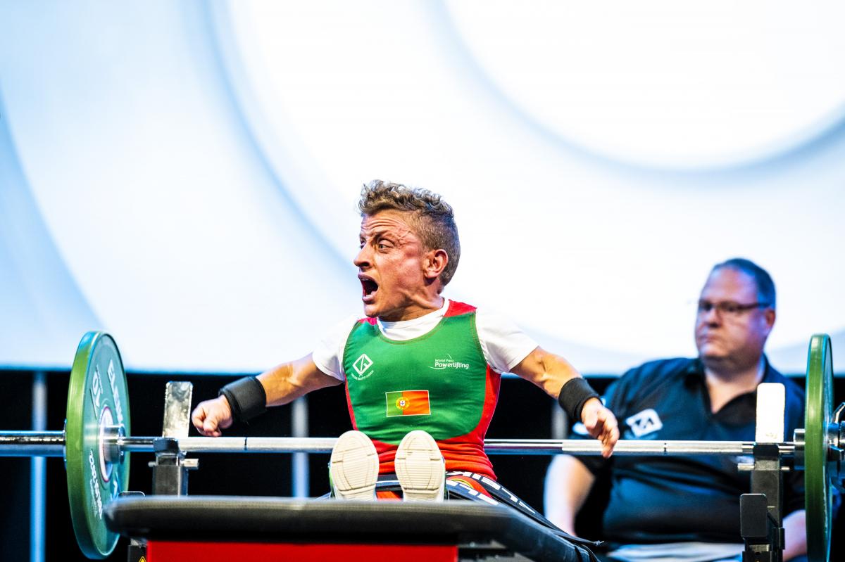 A female Para powerlifter celebrates with a cheer on the bench after a successful lift.