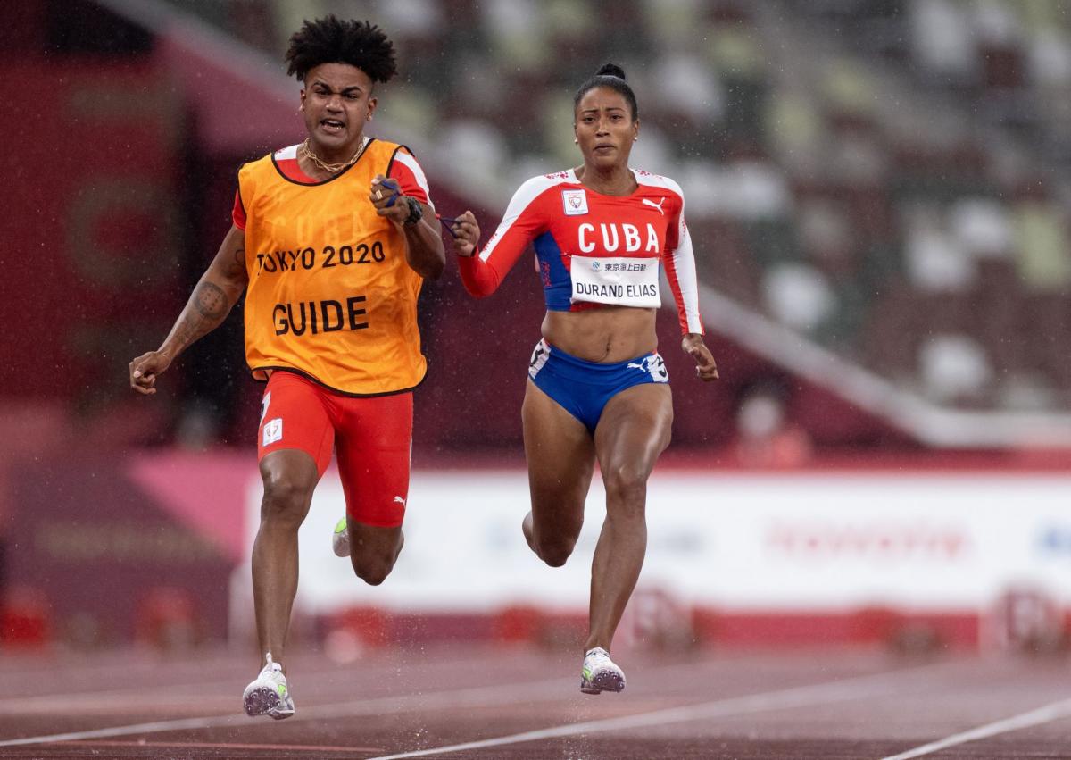 A female Para athlete runs with her male guide runner