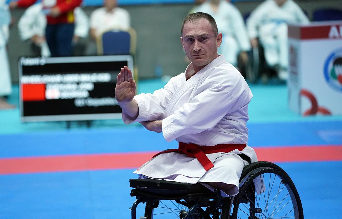 A male athlete wearing a white karate uniform performs during a competition