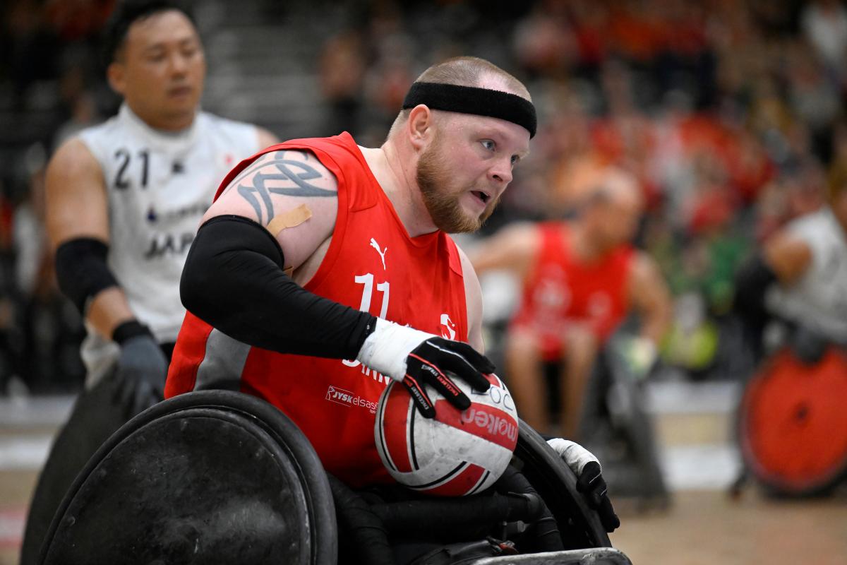 A male wheelchair rugby player carries the ball during a game