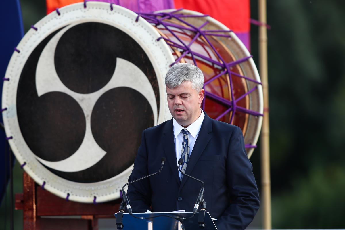 A man in a suit with a vision impairment speaks at a podium on a stage.