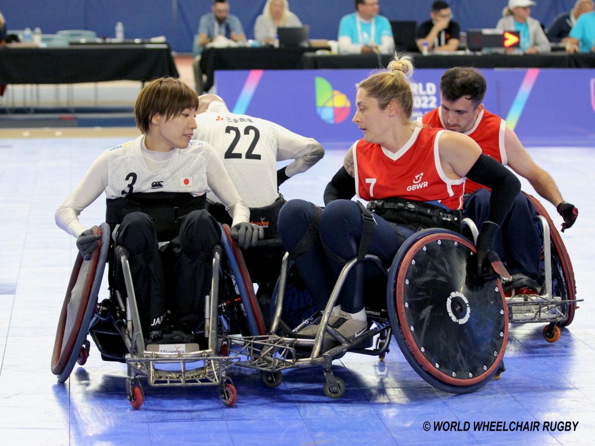 Two female wheelchair rugby players compete.