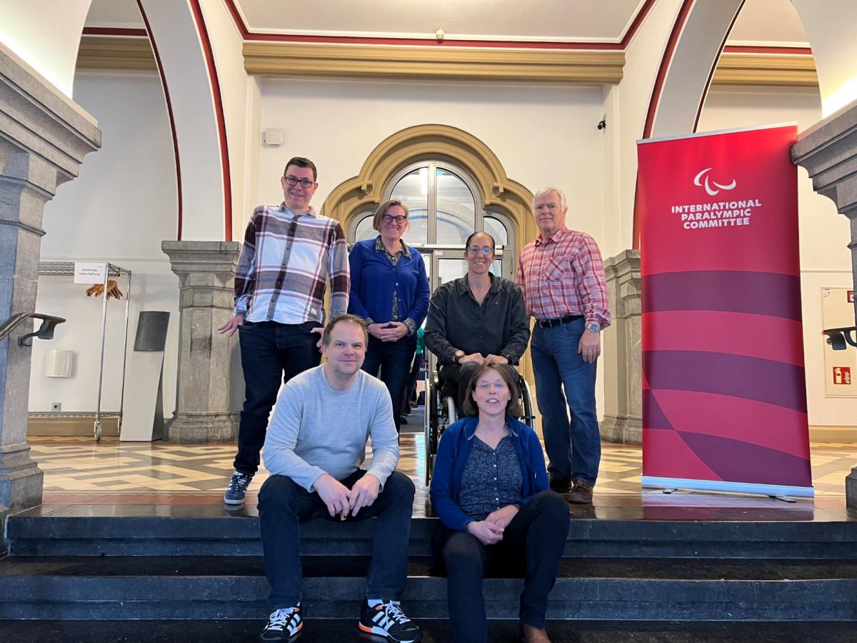 Six members of the Classification Compliance and Oversight Committee pose for a photo on the steps of an office building.