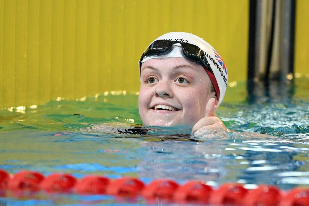 A female swimmer smiling from inside the pool