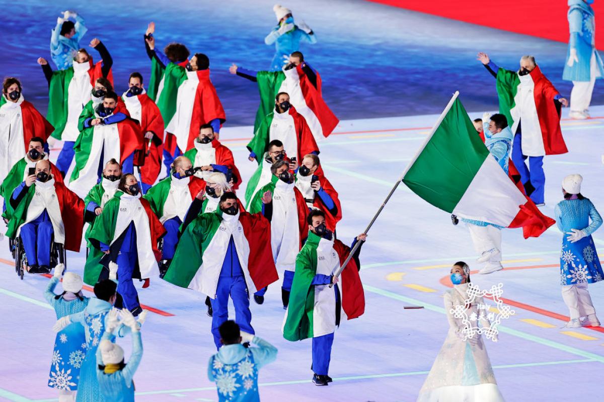 A group of about 15 athletes dressed in Italy's uniform march into the Opening Ceremony of the Beijing 2022 Paralympic Games.