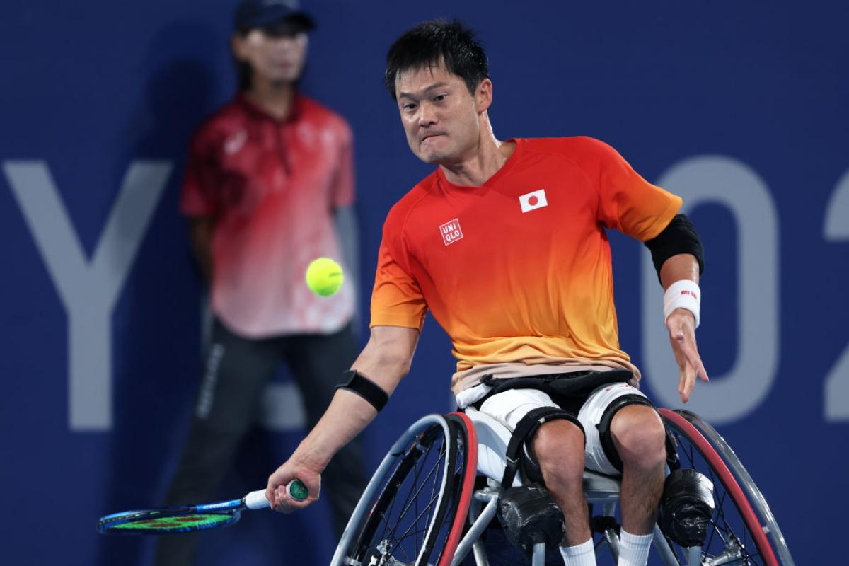A male wheelchair tennis player prepares to hit a ball.