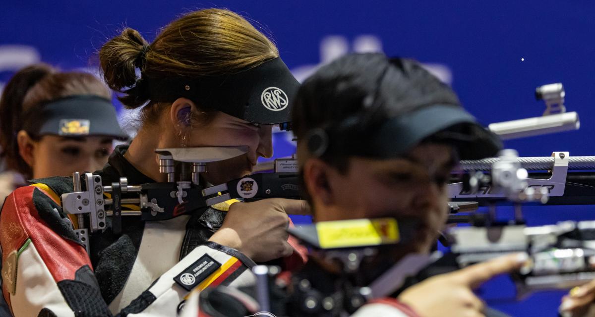 Three women competing in rifle shooting Para sport event indoors