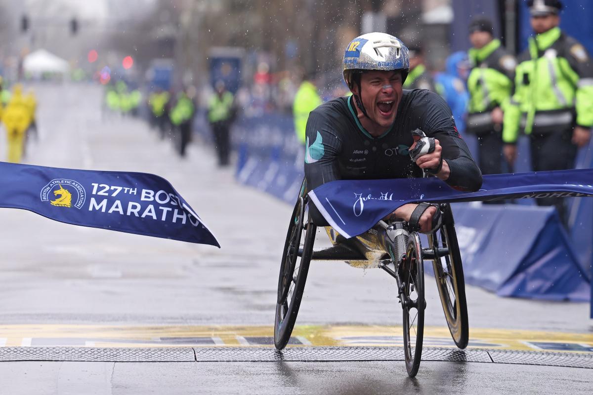 A male wheelchair racer crossing the finish line in a street marathon