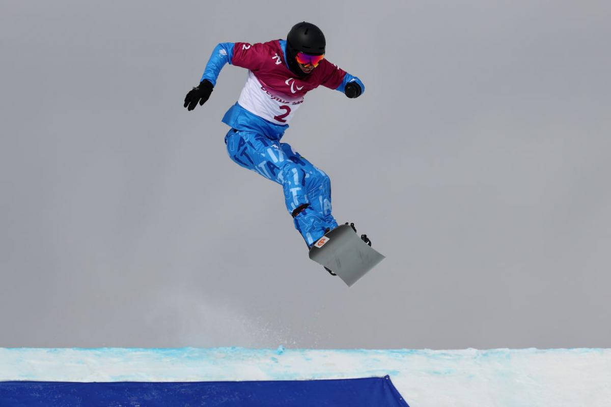 A male snowboarder jumps during his race.
