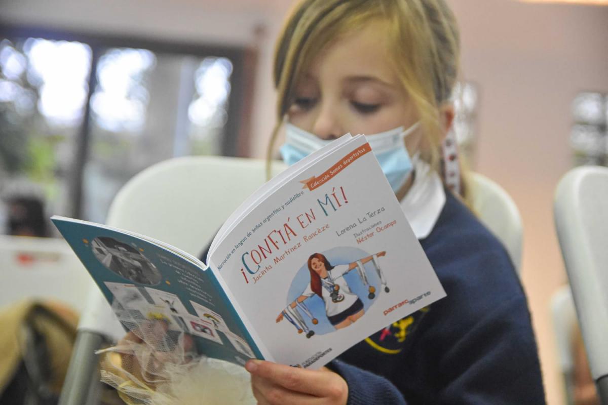 A young girl reads a children's book with a Para athlete on the cover.