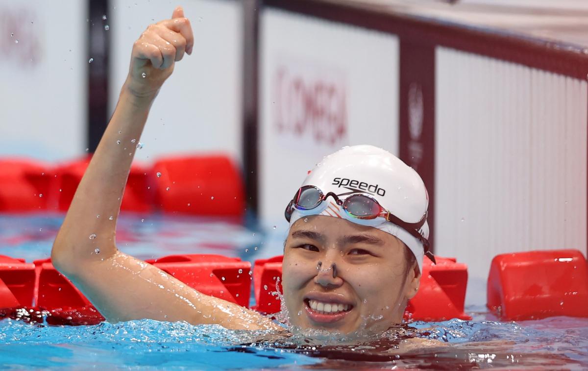 A female swimmer waving from inside the pool