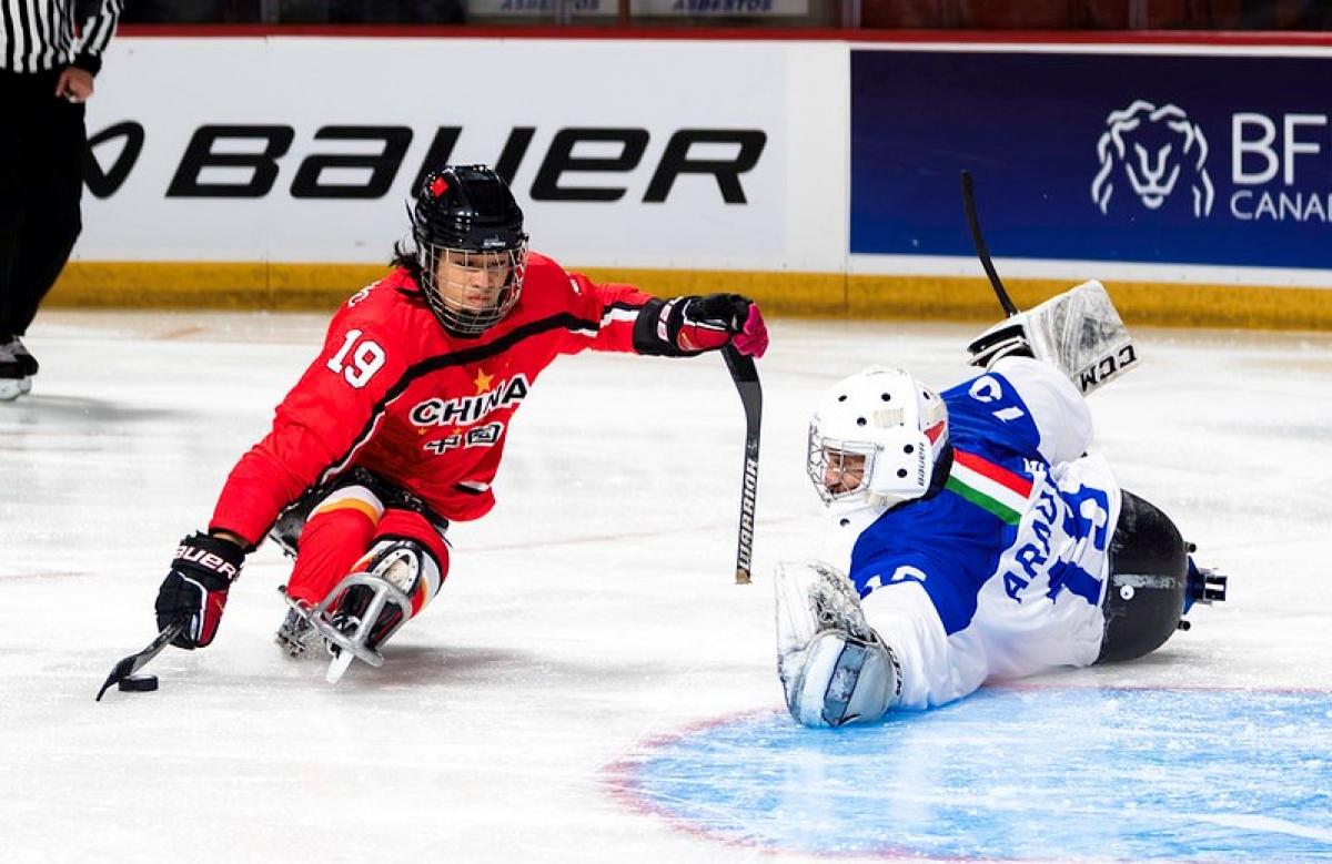 A  Para ice hockey player taking a shot in front of a goaltender