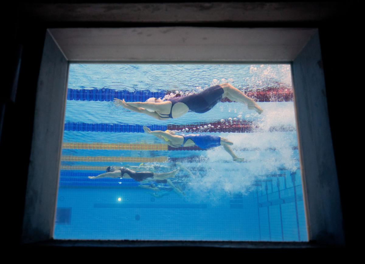An image of three female Para swimmers from a window at the bottom of the pool