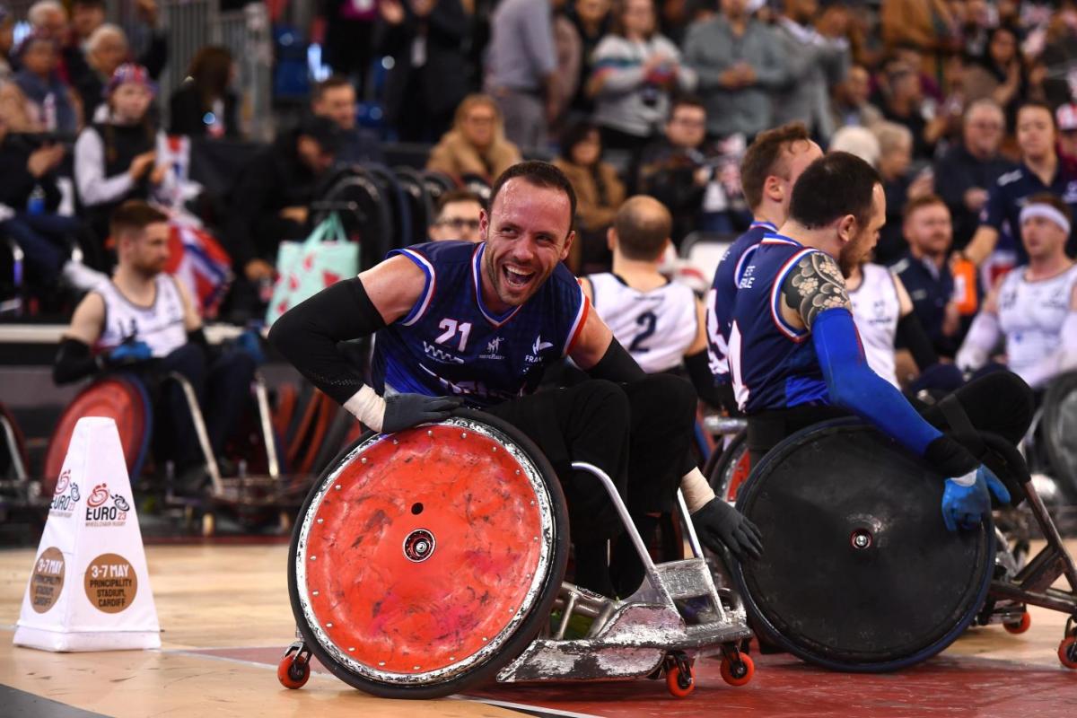 A male wheelchair rugby player smiles on the court.